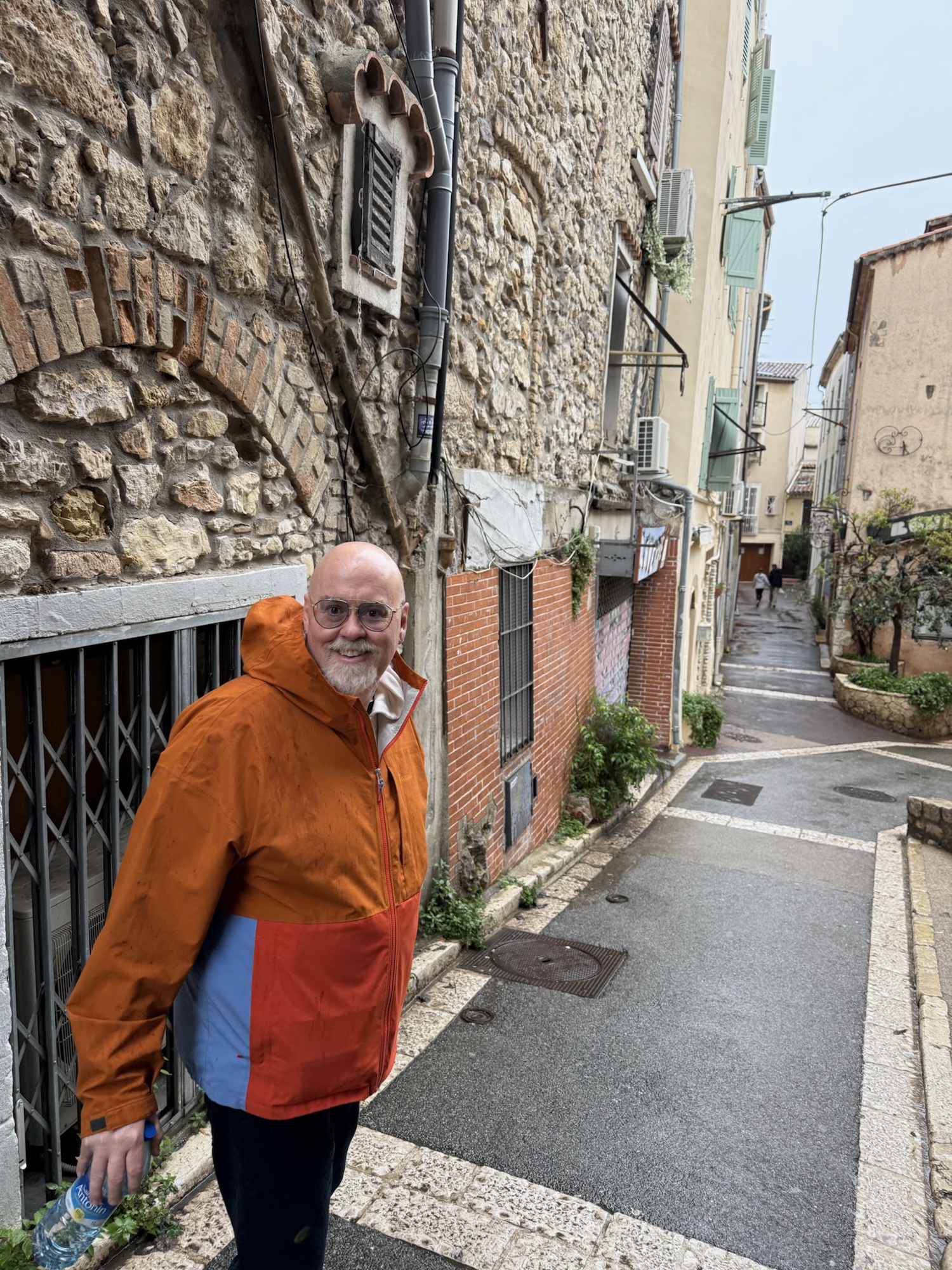 David smiling in a narrow French village street with blue shutters